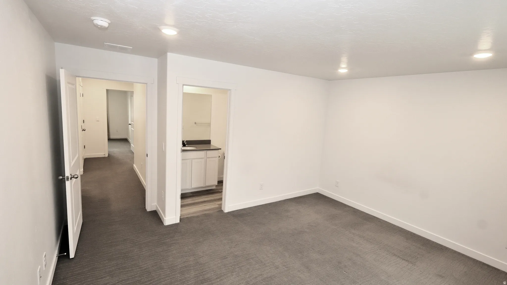 Spacious room featuring gray carpet, recessed lighting, and white baseboards