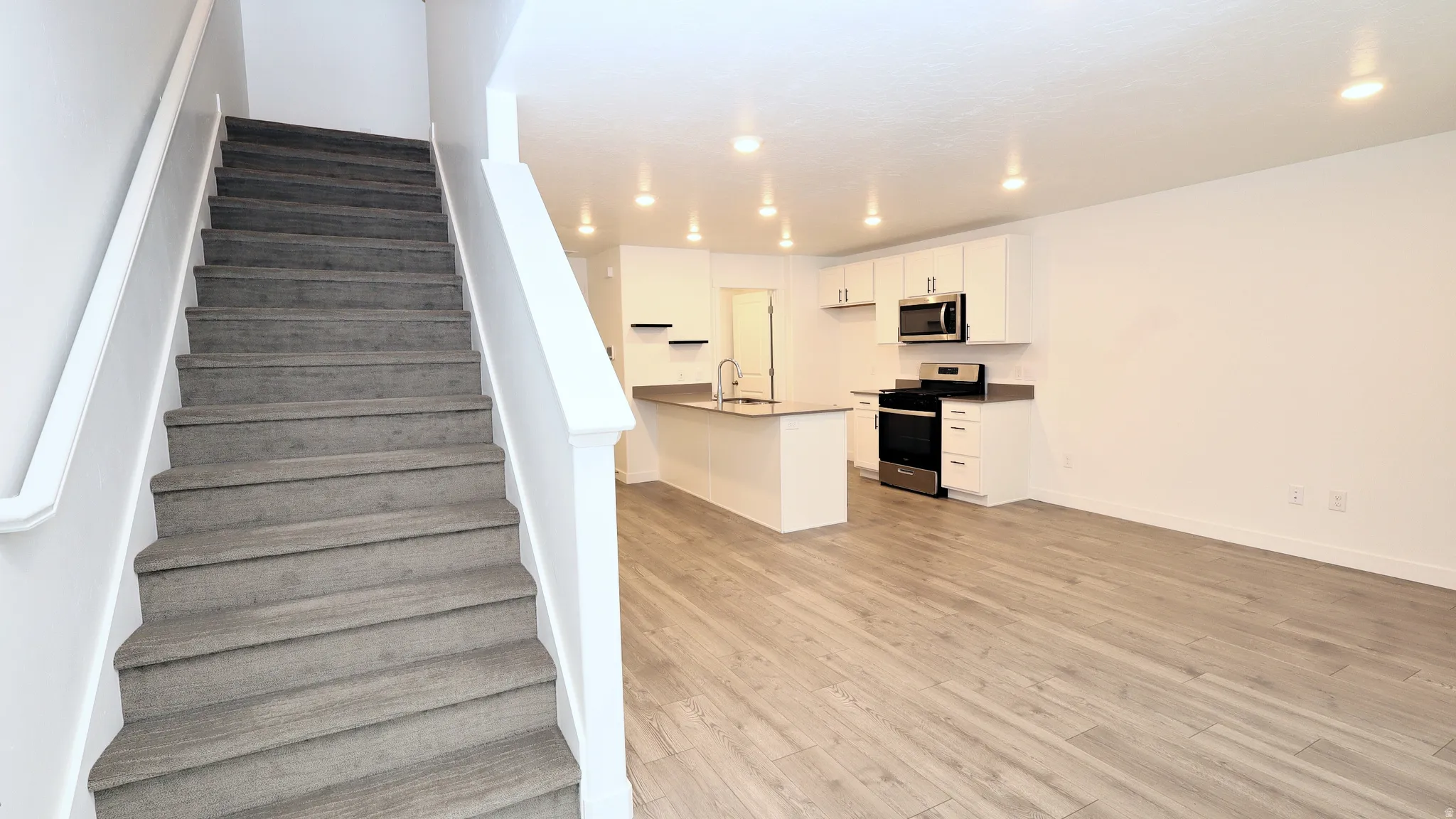 Open-concept living area featuring wood-finish flooring and a contemporary kitchen
