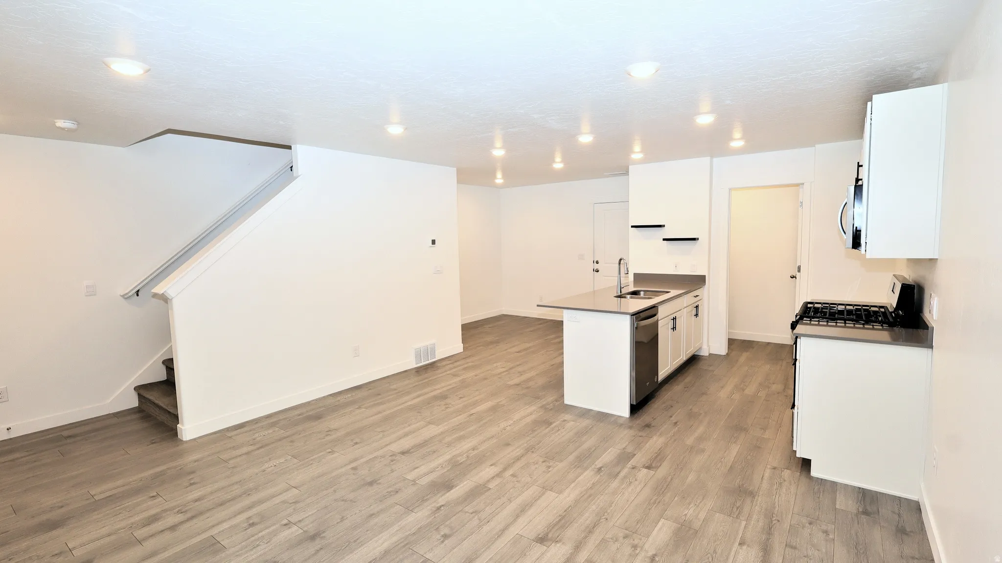Open-concept living space featuring wood-finish flooring, recessed lighting, and a modern kitchen