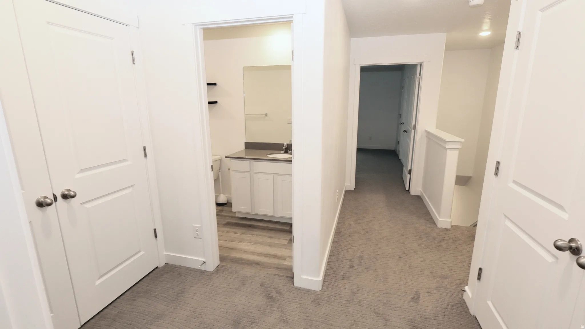 Hallway with neutral carpeting, white doors, and recessed lighting