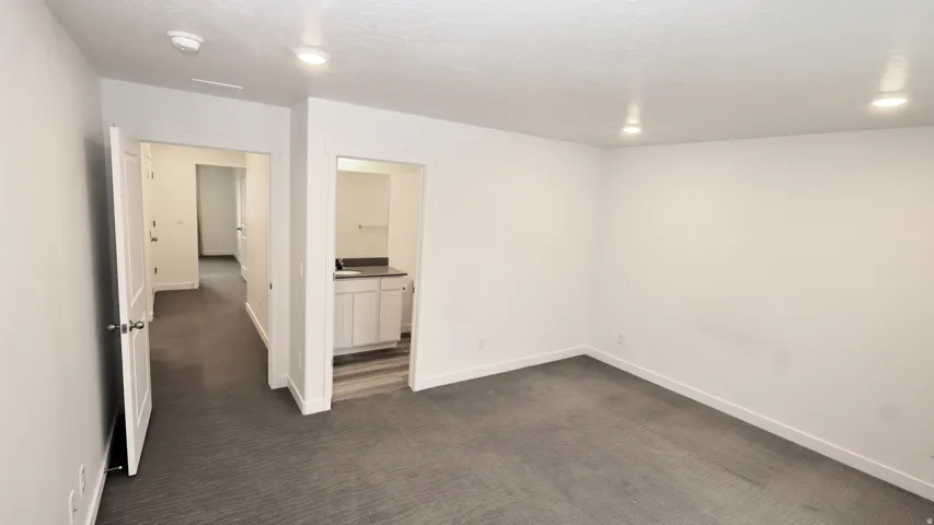 Spacious room featuring gray carpet, recessed lighting, and white baseboards