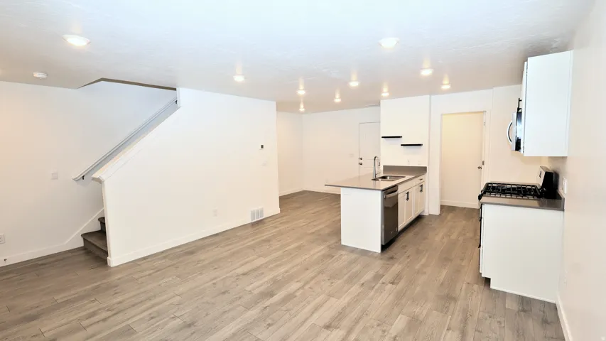 Open-concept living space featuring wood-finish flooring, recessed lighting, and a modern kitchen