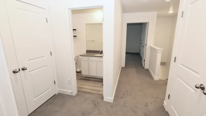 Hallway with neutral carpeting, white doors, and recessed lighting