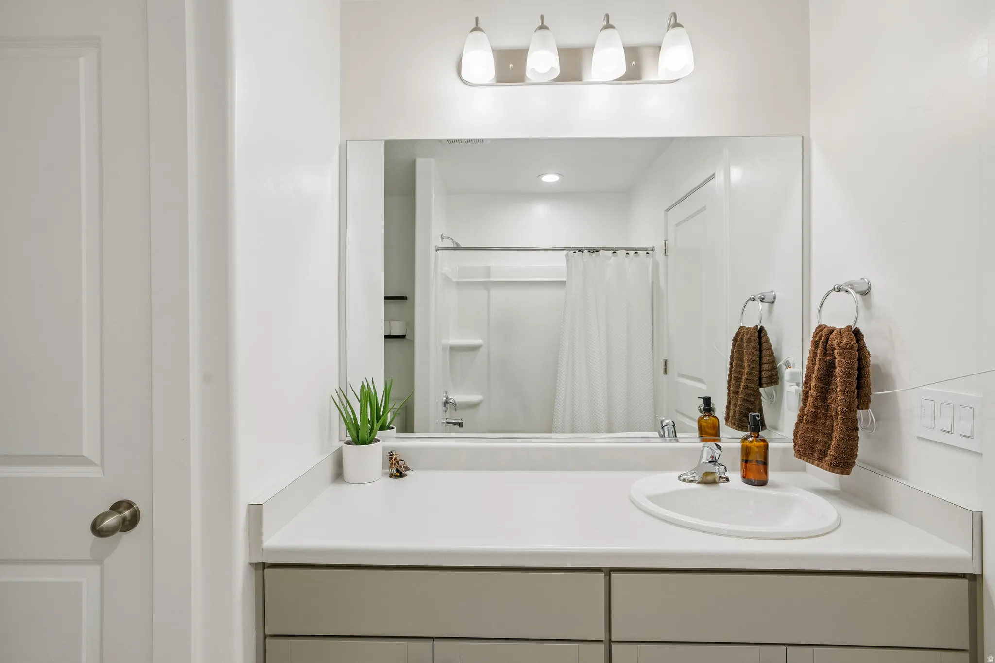 Bathroom vanity featuring a light-toned countertop, undermount sink, and polished chrome faucet