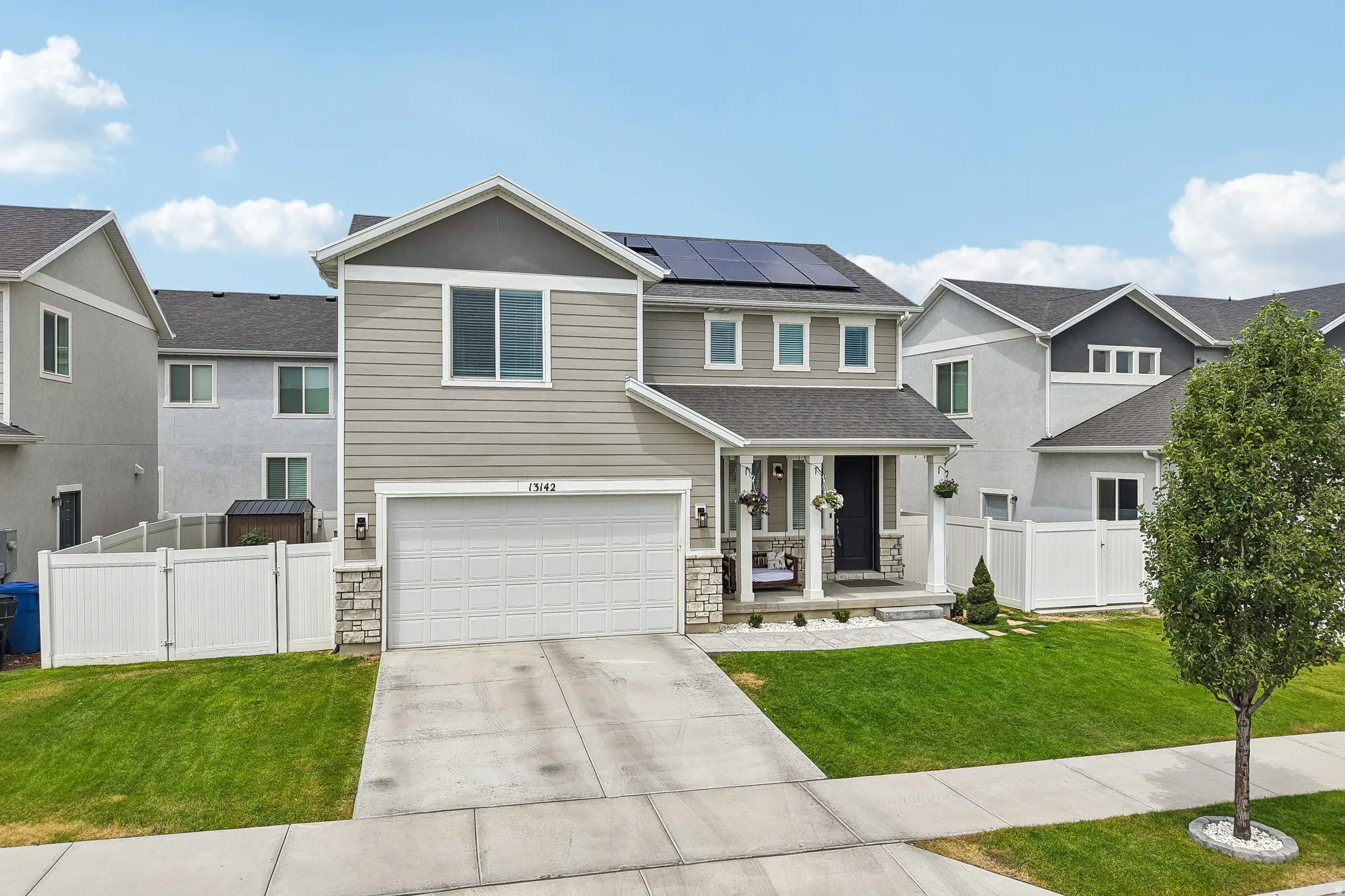 Contemporary two-story residence featuring light gray siding and stone accents