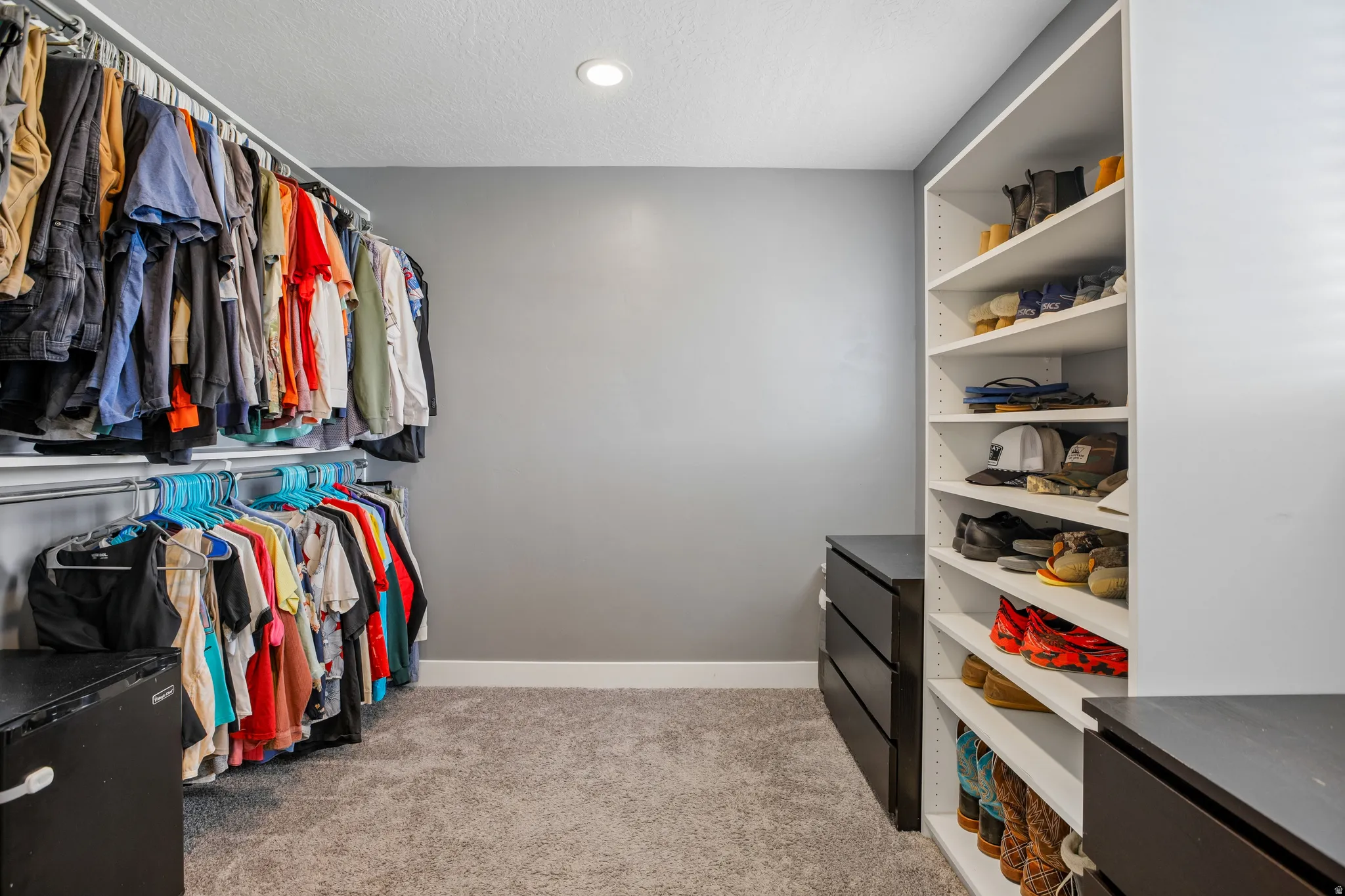 Custom closet featuring extensive hanging storage, built-in shelving, recessed ceiling lighting, and soft carpet flooring