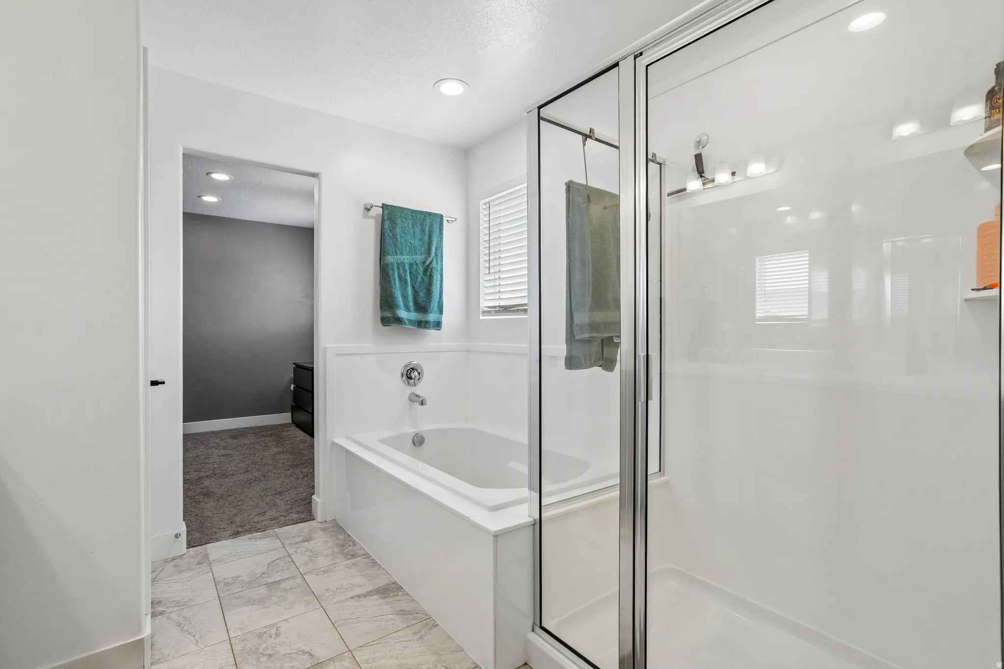 Bathroom featuring a built-in tub, a glass-enclosed shower with a chrome fixture, recessed lighting, and tile flooring