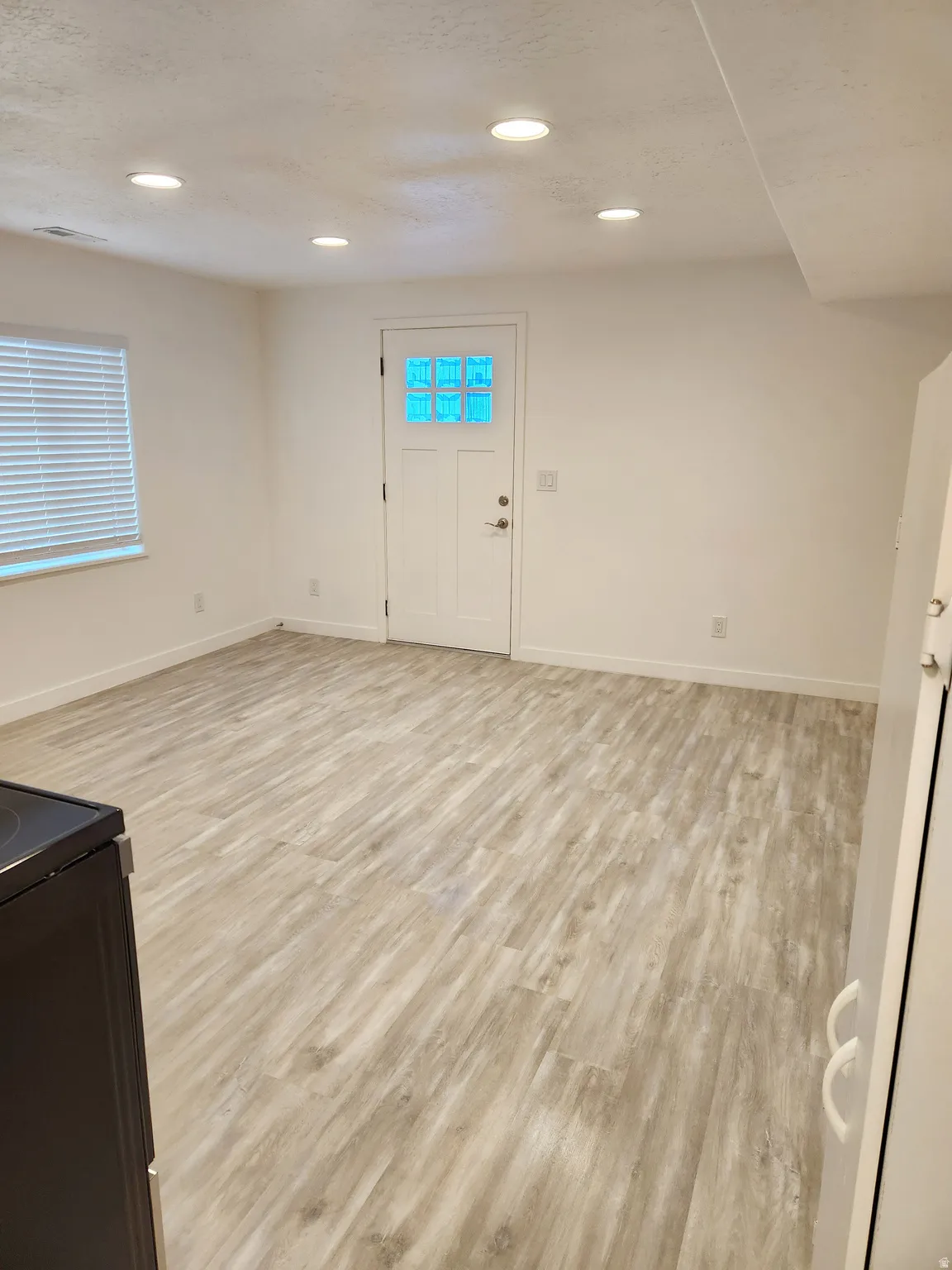 Spacious room with wood-finish flooring, recessed lighting, and a window with blinds
