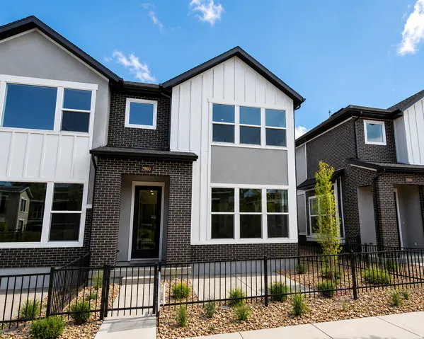 Contemporary townhouse exterior featuring a striking blend of dark brick, white vertical siding, and grey stucco accents