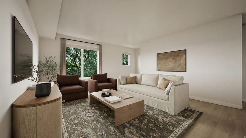 Living area featuring large windows with verdant outdoor scenery, light wood-finish flooring, and a neutral color palette