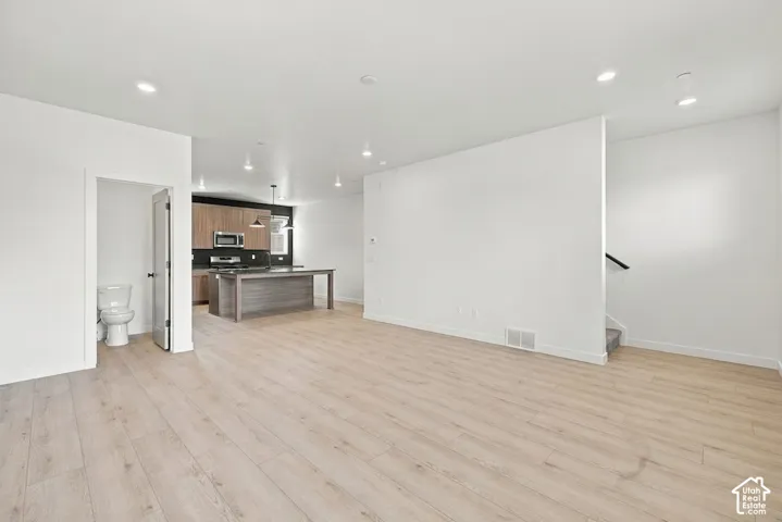 Open-concept interior featuring light wood-finish flooring, recessed lighting, a kitchen island, and flat-panel cabinetry