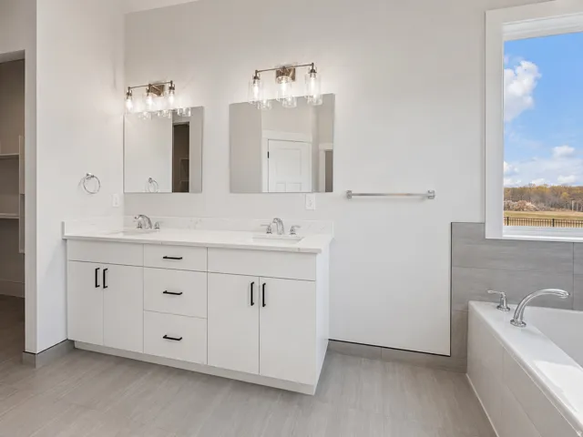 Bathroom with dual vanity featuring white cabinetry, integrated sinks, and quartz countertops