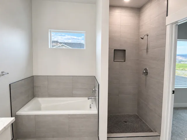 Modern bathroom featuring a tiled soaking tub and a walk-in shower with a recessed niche