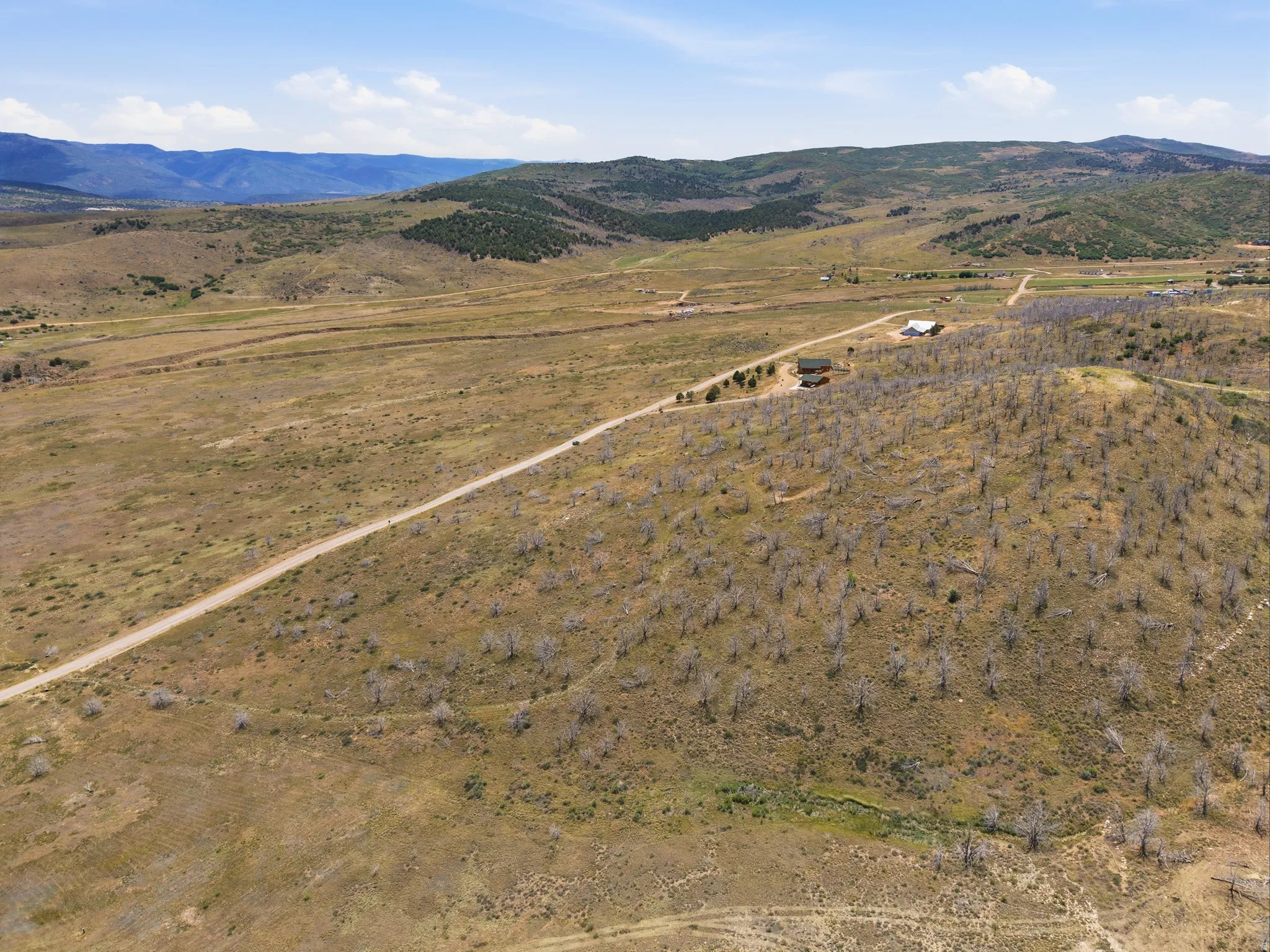 Expansive rural landscape featuring a single-family residence, an additional auxiliary building, and a long gravel driveway