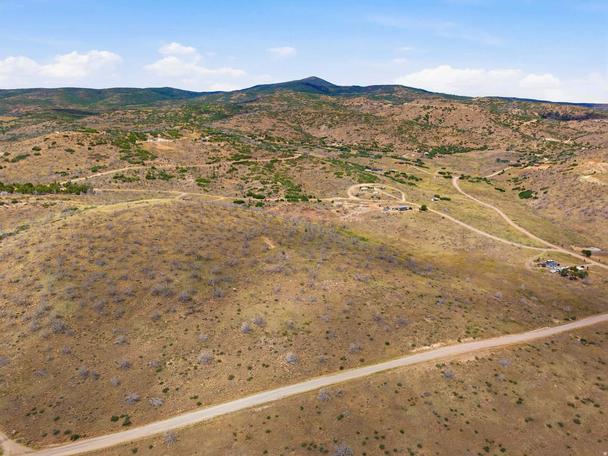 Expansive mountain landscape featuring varied terrain, a winding road, and distant structures
