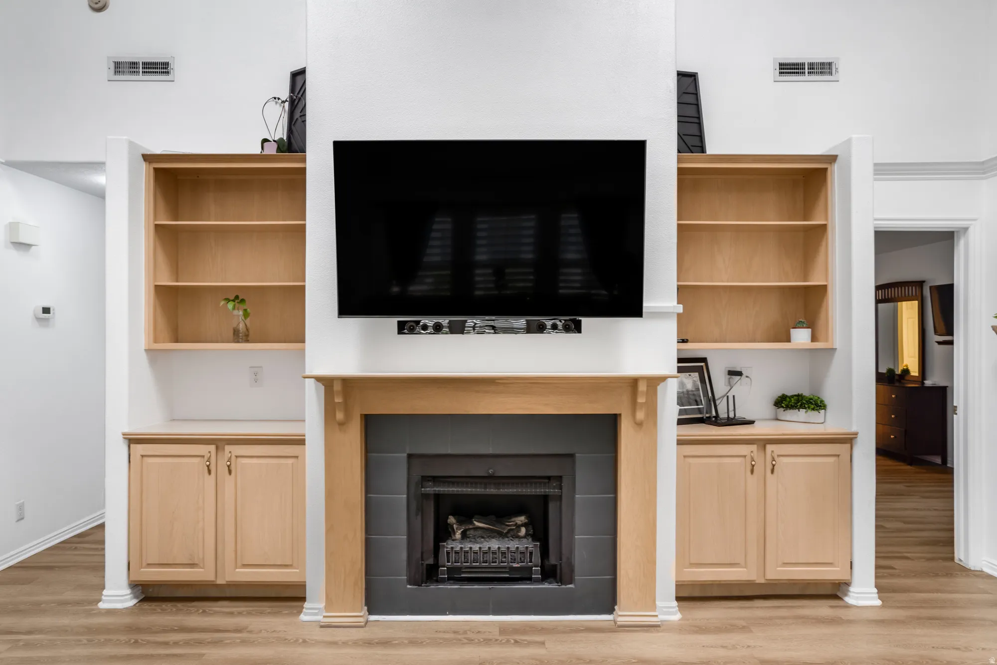 Central fireplace featuring a light wood mantelpiece, a dark tile surround, and a black firebox