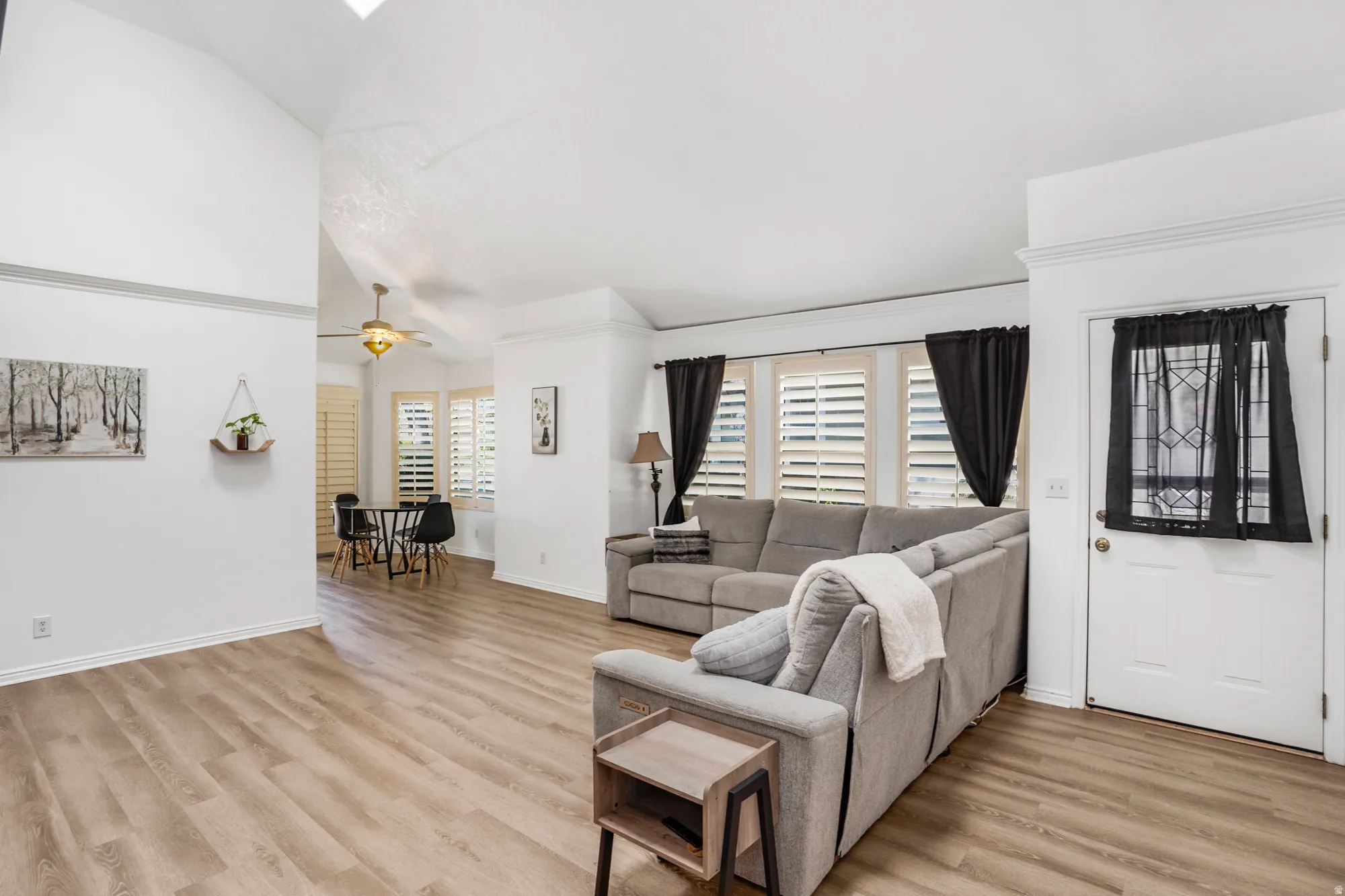Open concept living area featuring wood-finish flooring, vaulted ceilings, and white baseboards