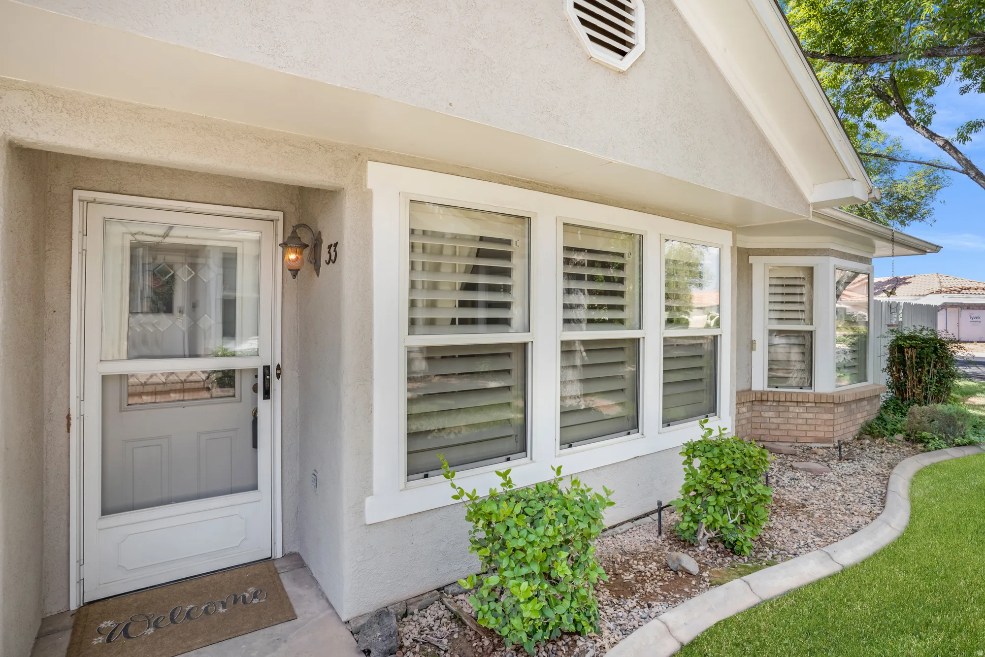 Stucco exterior with a covered entry and a white storm door