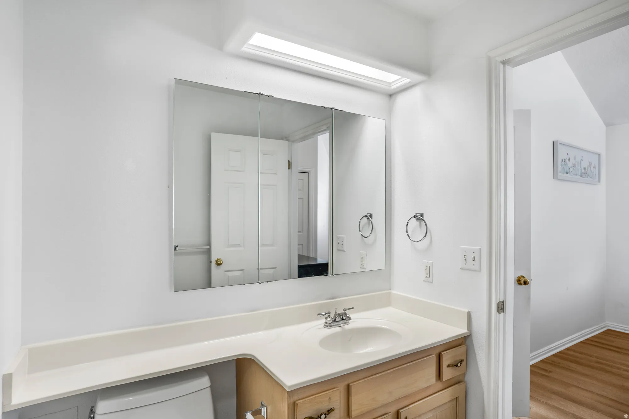 Bathroom vanity featuring an integrated sink, laminate countertop, and wood-finish cabinetry