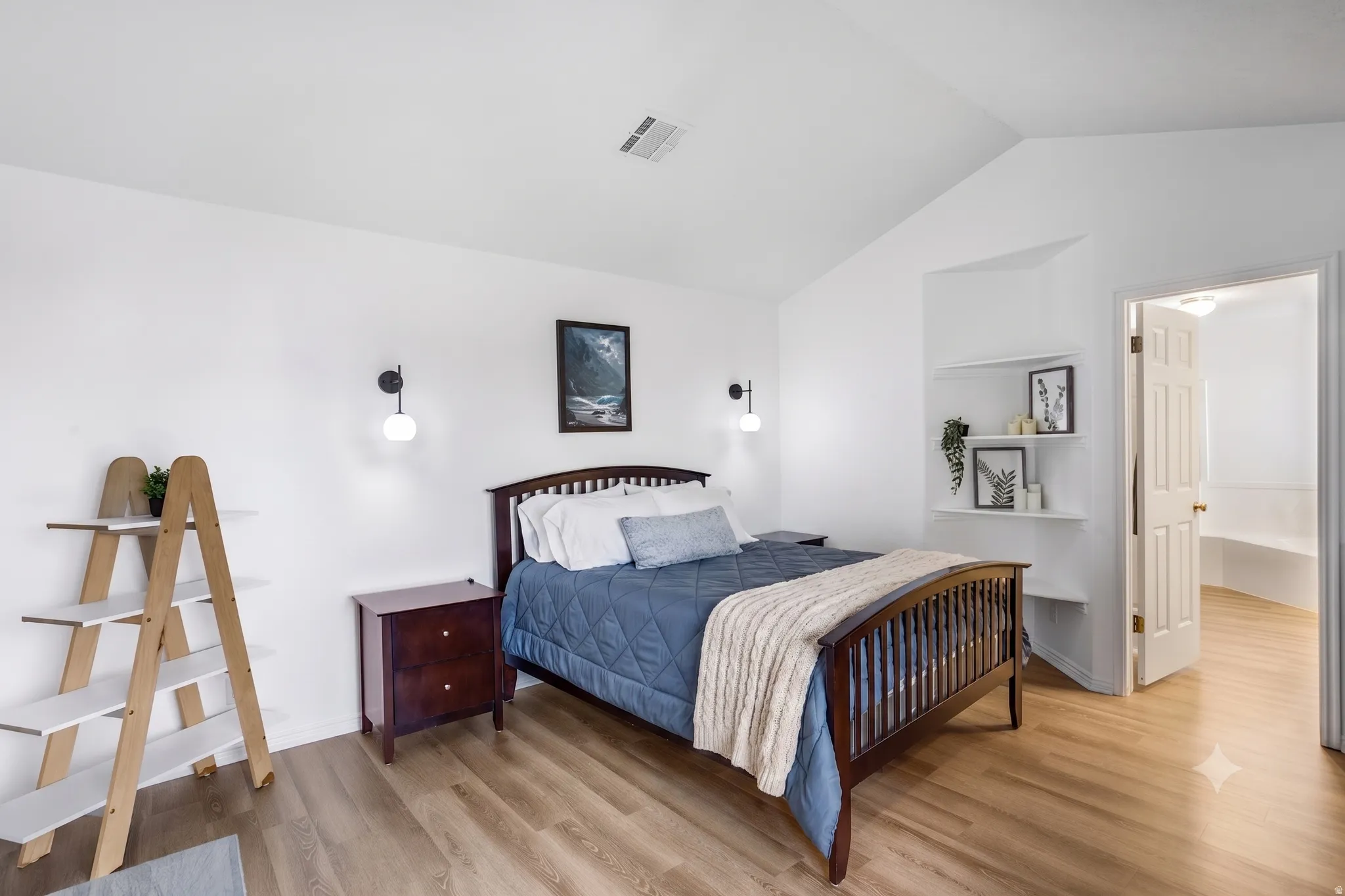 Bedroom featuring wood-finish flooring, vaulted ceiling, and recessed wall shelving
