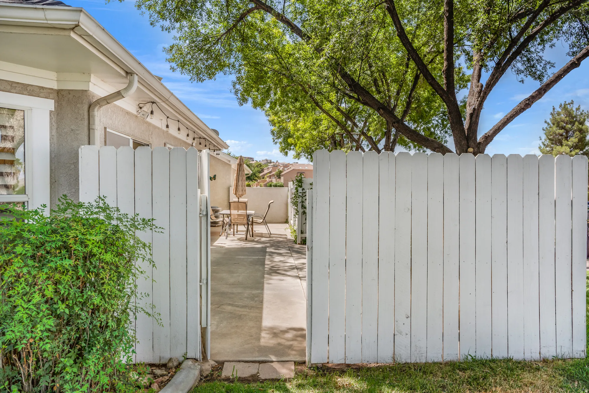 Private patio area featuring a white picket fence, concrete paving, and a stucco exterior