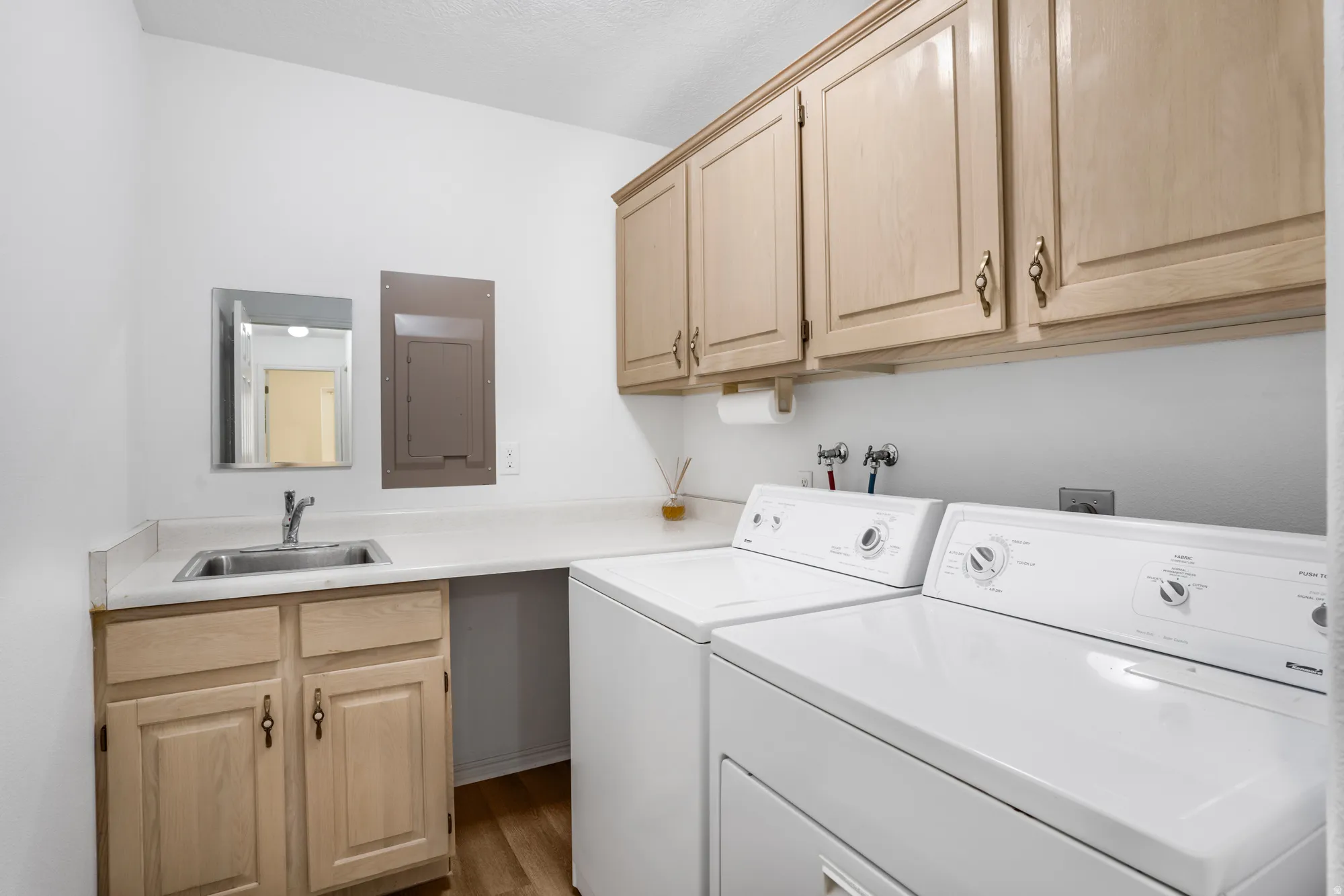 Laundry area featuring light wood-finish cabinetry, a utility sink, and a white countertop