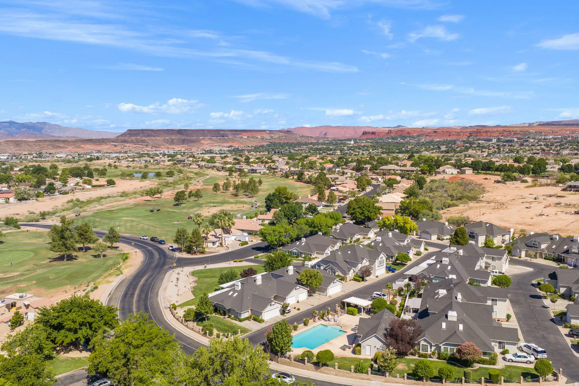 Residential community featuring a curved street layout, a central swimming pool, and uniform rooflines