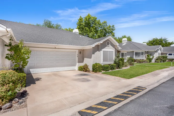 Stucco exterior residence with an attached two-car garage, concrete driveway, and a shingle roof. AI-repaired lawn.