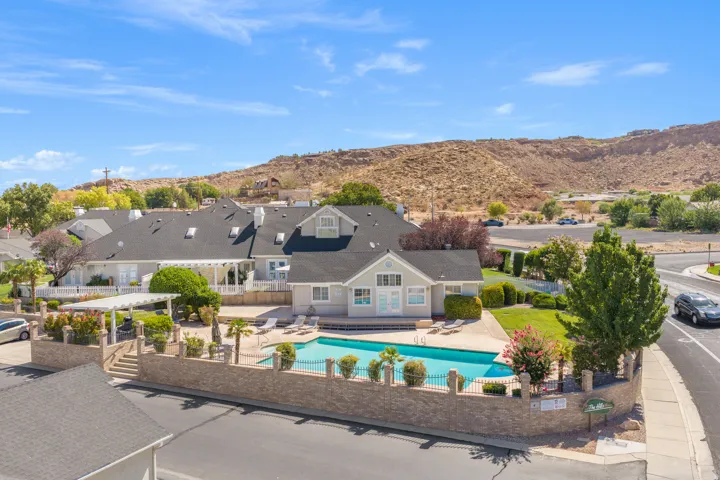 Community swimming pool with surrounding patio space, a decorative stone wall, and established landscaping