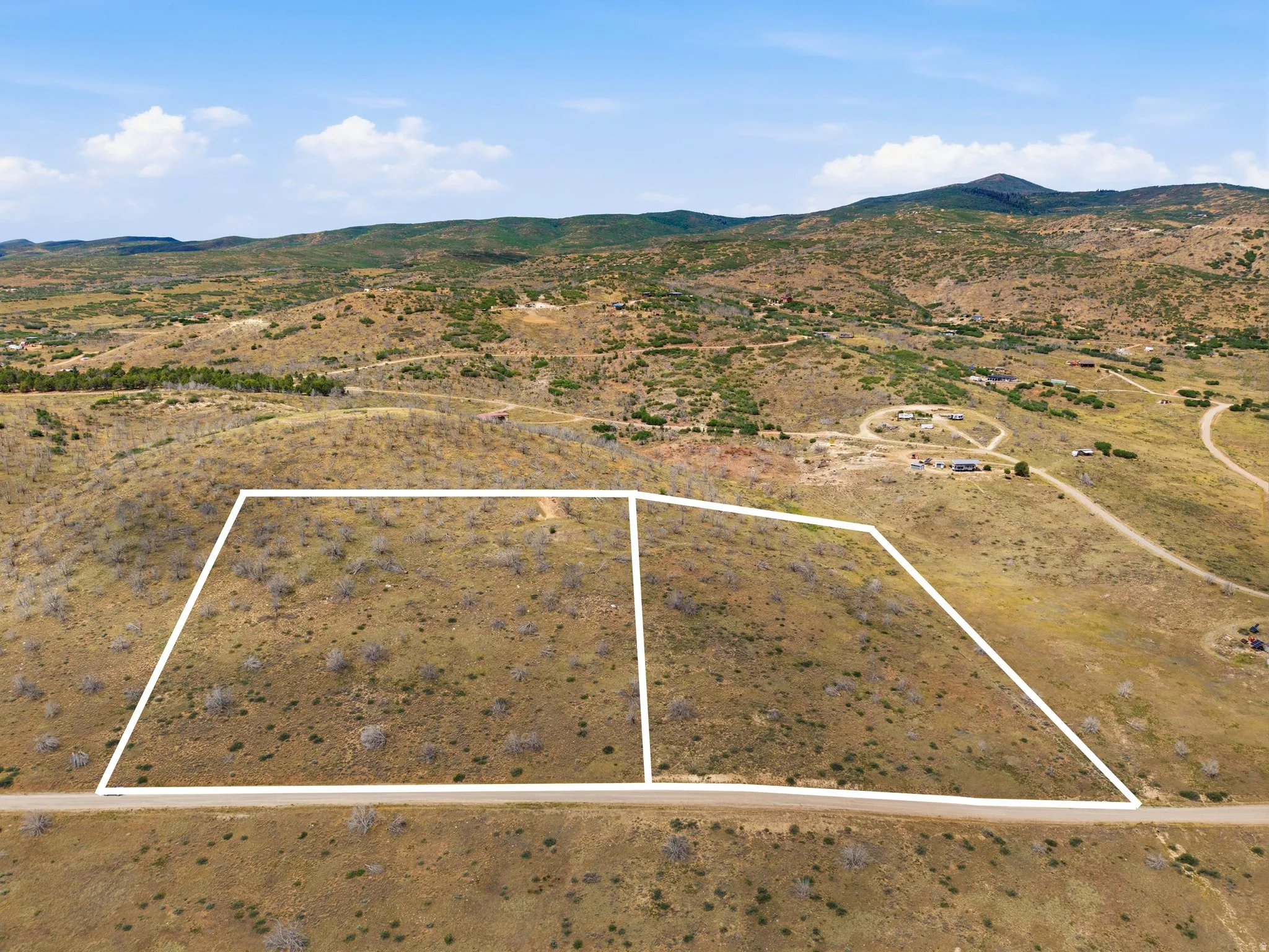Expansive land parcels outlined in white, featuring natural terrain and distant mountainous backdrops