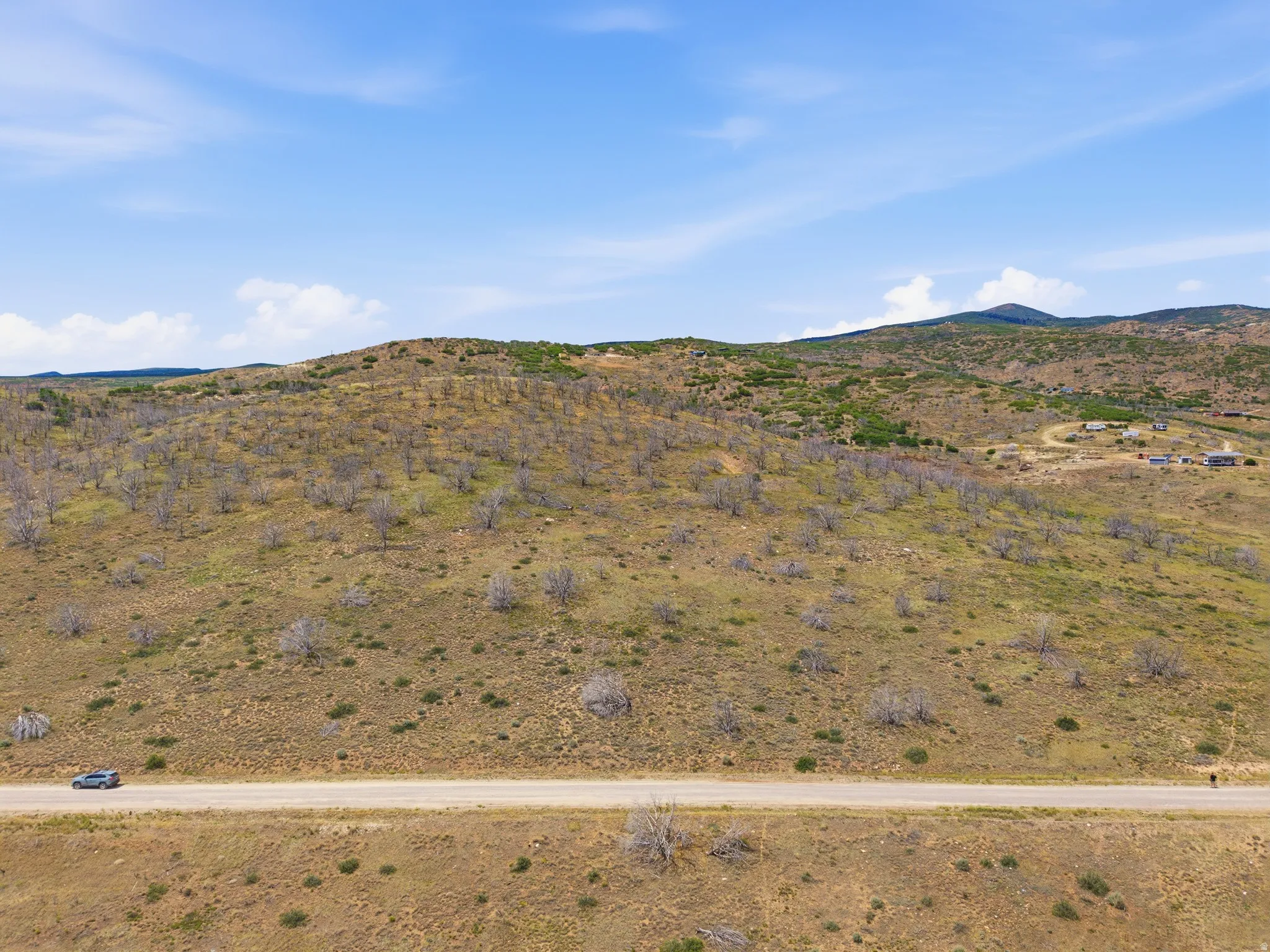 Expansive undeveloped land featuring rolling hills and distant mountain ranges under a clear sky