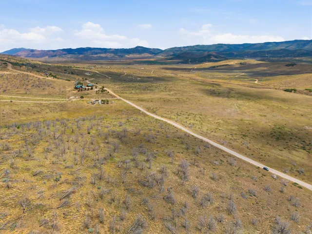 Expansive rural landscape featuring a single-story residence with a green roof, surrounded by vast open land