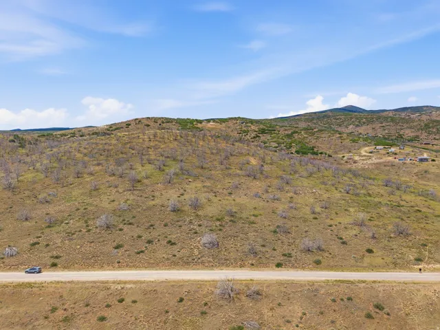 Expansive undeveloped land featuring rolling hills and distant mountain ranges under a clear sky