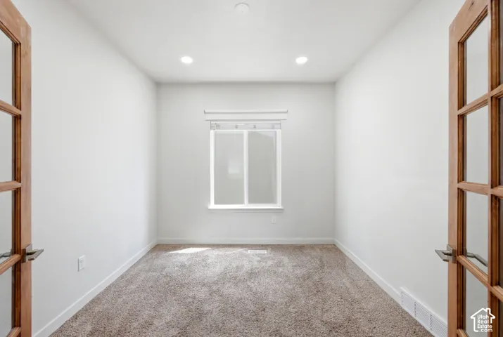 Room featuring white walls, recessed ceiling lights, and light brown carpet flooring