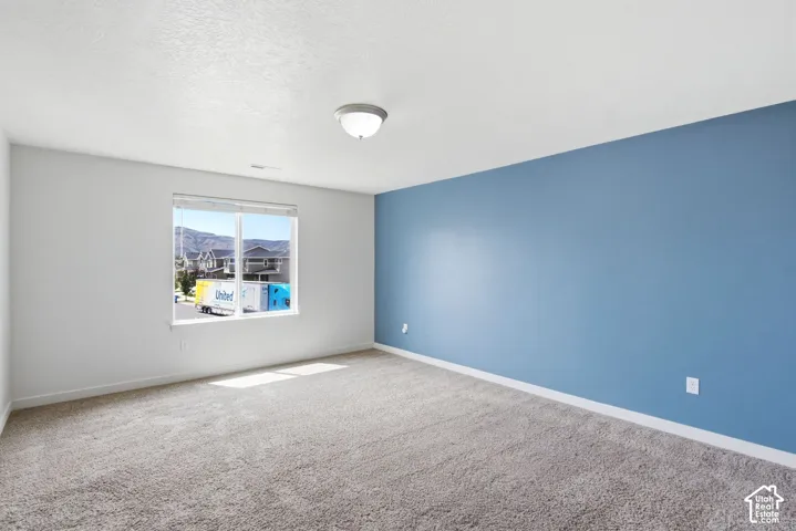 Carpeted room with a blue accent wall, white trim, and a window