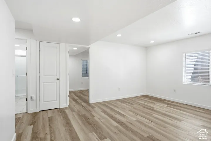 Spacious room with wood-finish flooring, recessed lighting, and a window with horizontal blinds