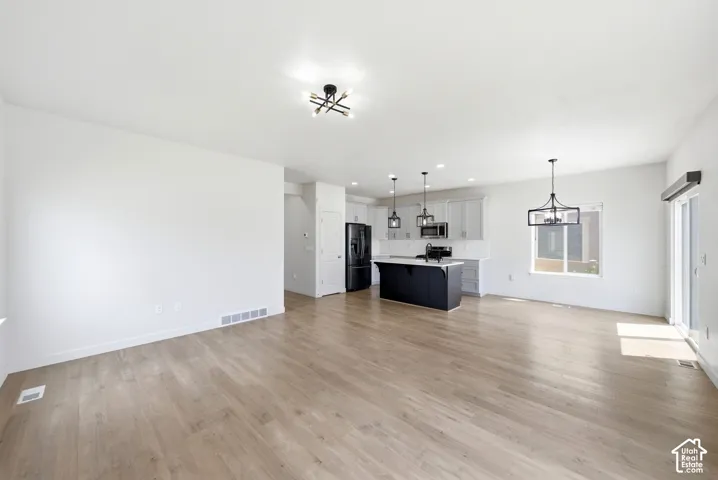 Expansive living area featuring light wood-finish flooring, white walls, and a contemporary ceiling fixture