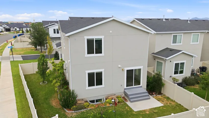 Rear exterior featuring a light gray stucco finish, white trim, and a dark shingle roof