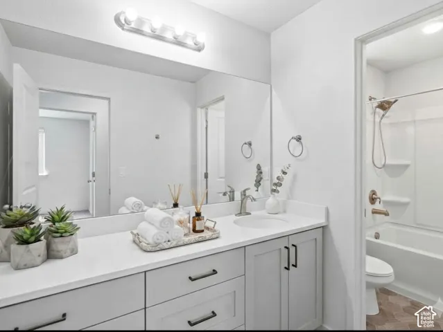 Bathroom vanity featuring a light-toned countertop, integrated sink, and gray cabinetry with dark hardware