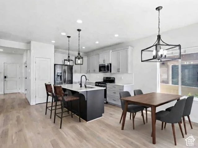 Modern kitchen featuring light wood-finish flooring, white cabinetry, and a dark island with seating