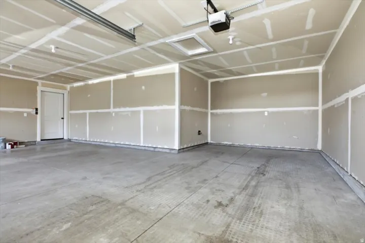 Spacious garage featuring a concrete floor, exposed drywall with joint compound, and a white interior door