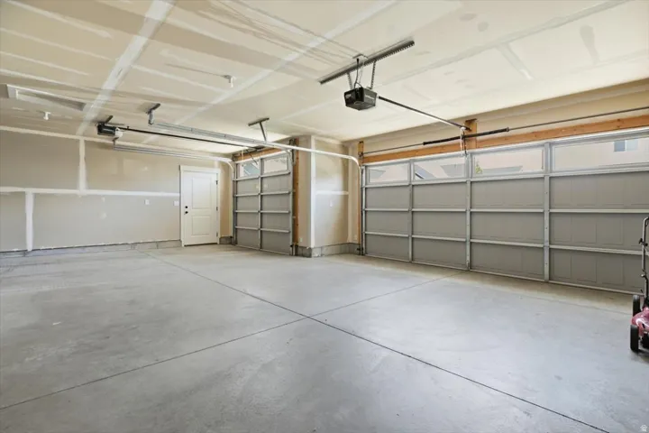 Spacious garage featuring a concrete floor, two overhead garage doors with frosted window panels, and an interior access door