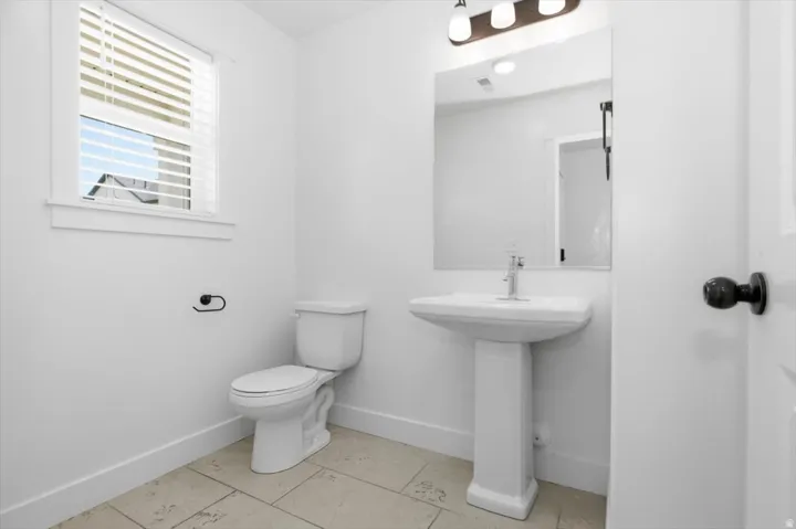 Bathroom featuring a pedestal sink, white toilet, and tiled flooring