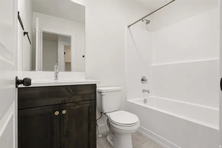 Bathroom featuring a dark wood-finish vanity with a white countertop, chrome faucet, and rectangular mirror