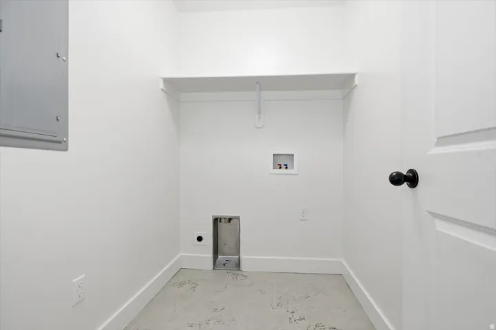 Dedicated utility space featuring a built-in shelf, appliance hookups, and a panel door with a black knob