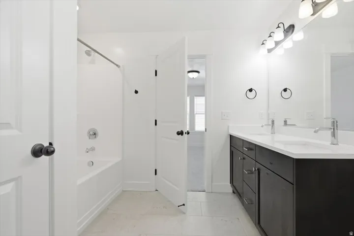 Bathroom featuring a dual vanity with a white countertop, dark wood-finish cabinetry, and chrome fixtures