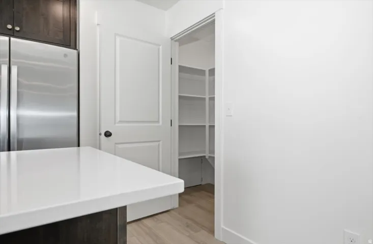 Kitchen featuring a stainless steel refrigerator, dark wood cabinetry, and a white countertop