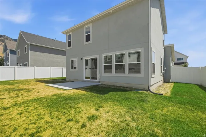 Backyard featuring a concrete patio, sliding glass door, and a white vinyl fence