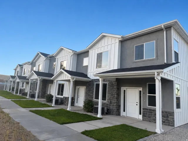 Contemporary townhome exterior featuring a two-tone facade with dark stone veneer and light stucco