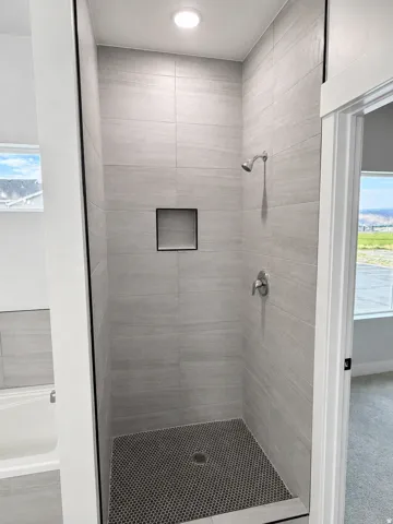Contemporary shower enclosure featuring large-format gray wall tile and a contrasting dark penny tile floor